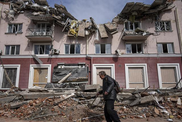 Un uomo passa davanti a un edificio danneggiato dai bombardamenti a Chernihiv,