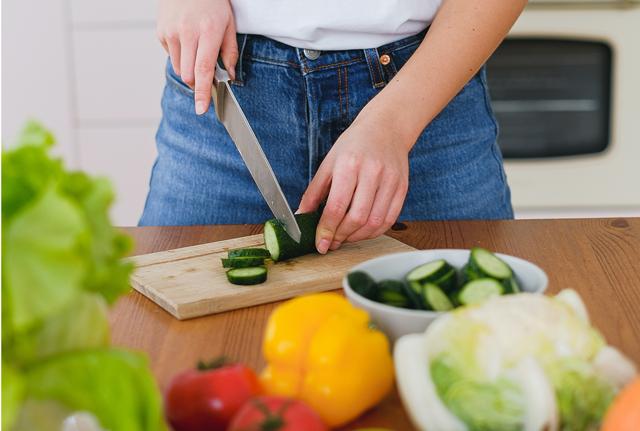 ragazza in cucina taglia un cetriolo